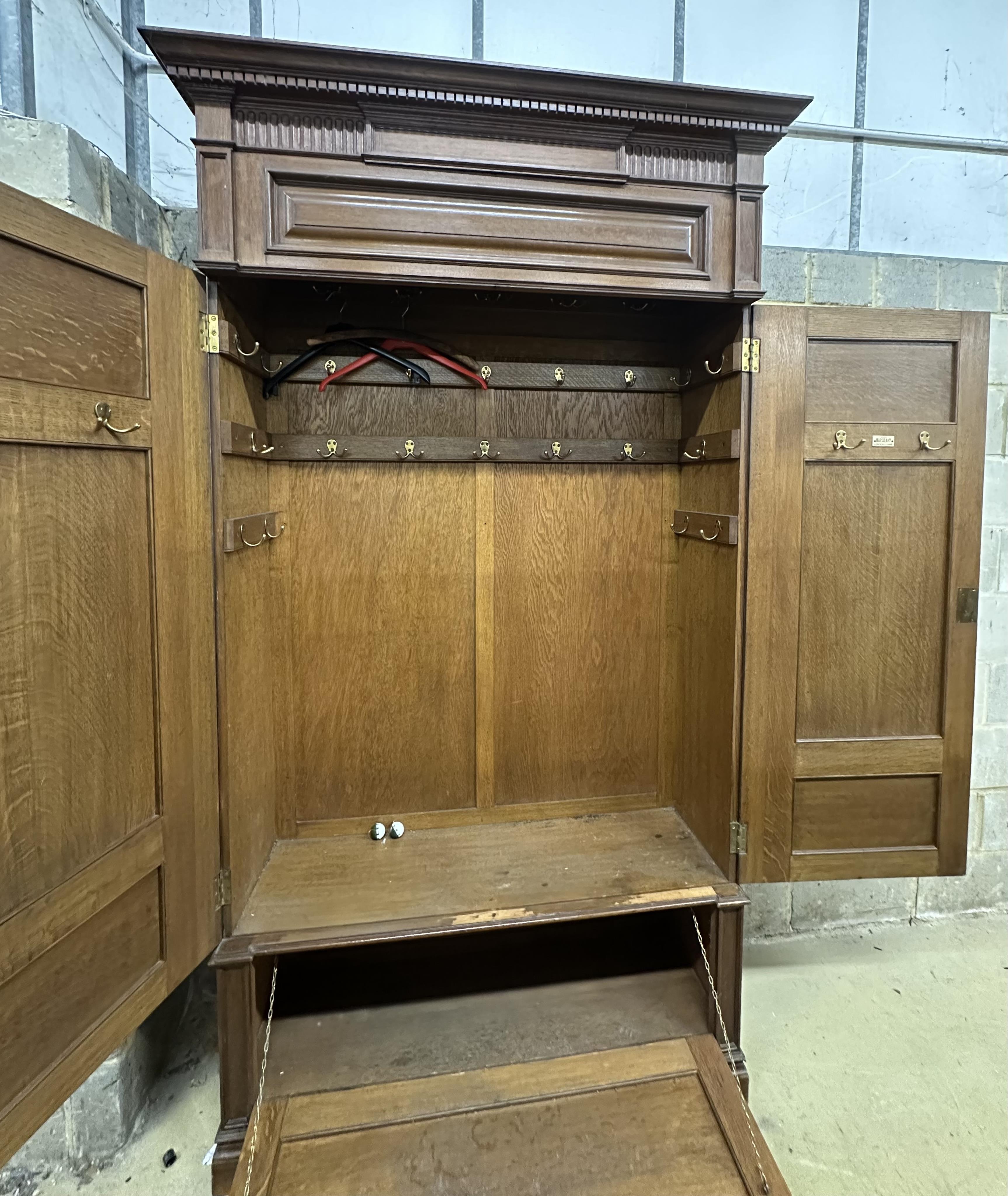 A late Victorian panelled oak wardrobe retailed by Maple & Co., width 124cm, depth 42cm, height 230cm. Condition - fair, two pieces of cornice timber missing